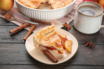 Plate with slice of freshly baked apple pie on table