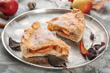 Metal plate with slices of freshly baked apple pie on table, closeup