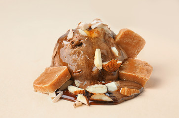 Chocolate ice cream ball with caramel sauce and candies on color background