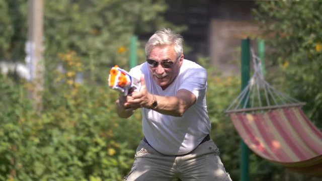 Senior man in a toy gun fight on nature
