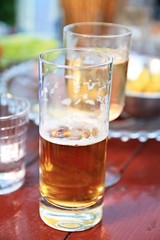 glass of beer sitting on a wooden table outside a pub