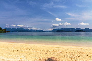 Fototapeta na wymiar Golden yellow sand on a deserted beach near the blue sea in bright Sunny day.