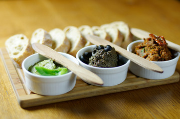 Spreads and bread rolls served on a wooden board. - obrazy, fototapety, plakaty