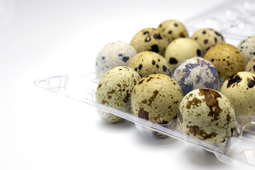 A photo of small quail eggs in the transparent plastic container on the white background. I like Healthy lifestyle, healthy eating food concept. Easter background.