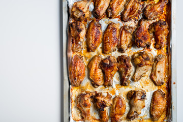 Chicken wings baked in a pan on white background isolated. Top flat, from above.