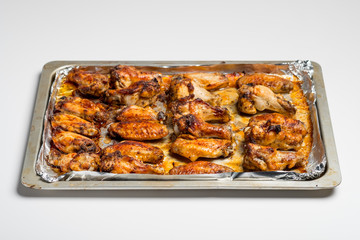 Chicken wings baked in a pan on white background isolated. Top flat, from above.