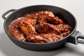 Chicken Wings BBQ in pan with red sauce. Fast food menu background isolated.