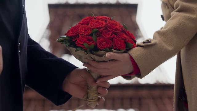 Guy showing his affection to girlfriend, presenting woman with bouquet of roses