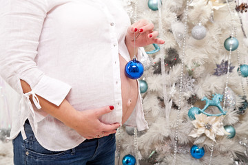 Tummy of a pregnant woman with a Christmas toy in her hands