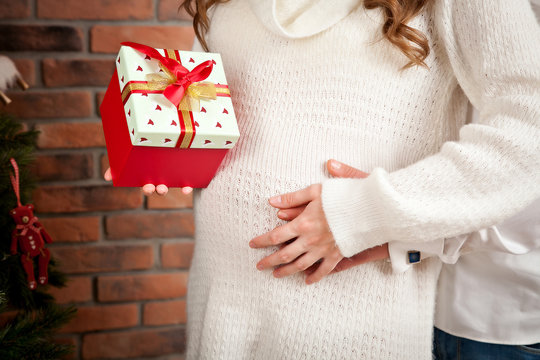 Tummy of a pregnant woman with a Christmas toy in her hands