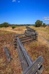 Fototapeta na wymiar zigzag fence in the middle of grass-land under the sun with blue sky