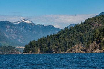 ocean landscape with mountains covered by forest and snow