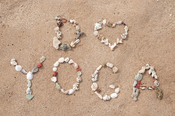 Writing with shells text I love Yoga on sandy beach
