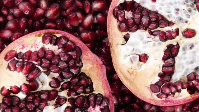 Rotating pomegranate fruit and seeds, top view, 4K.