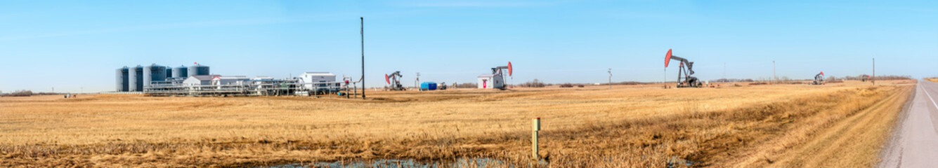 Gas oil distribution station with cisterns and a compressor on a yellow field with pumps pumping oil