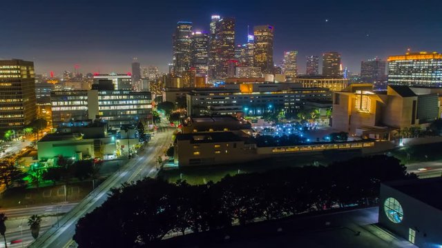 Cinematic urban aerial time lapse view of downtown Los Angeles with freeway traffic at night