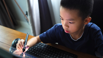Asian boy doing digital sketching on desktop computer closeup to face.