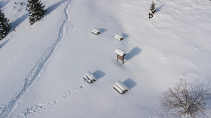 Picnic tables covered with snow flakes after the snowfall, aerial drone view