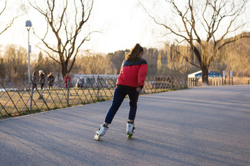 Skating woman on rollerblades in the park. Back view.
