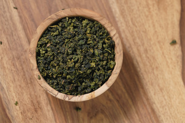 dry organic green oolong tea in wood bowl