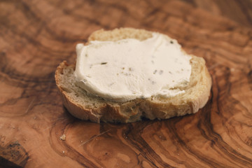 crunchy baguette slice with cream cheese on olive board