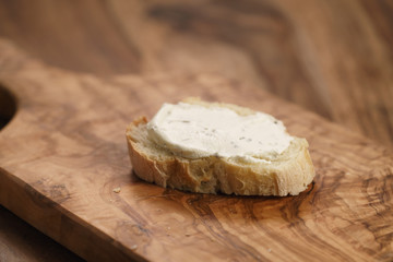 crunchy baguette slice with cream cheese on olive board