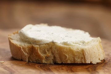 crunchy baguette slice with cream cheese on olive board