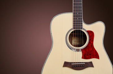 Close-up of guitar on brown background.