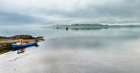 Alone boat driving through in the foggy sea in the scottish highlands