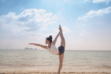 Young attractive woman doing yoga on beach