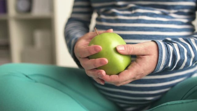 Pregnant woman holding green apple as symbol of health