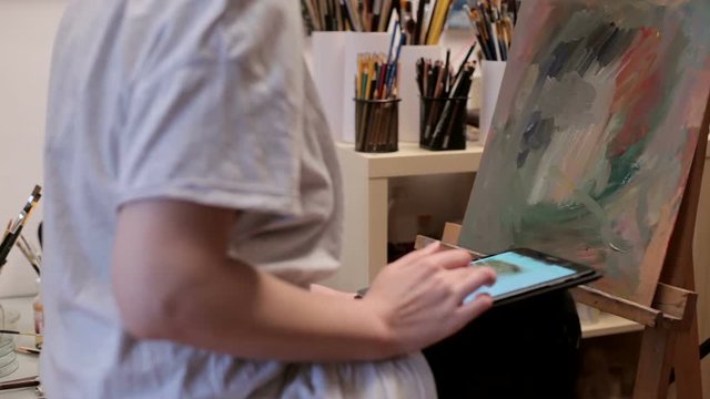 Painter In Her Shop Using A Digital Tablet To Surf The Web