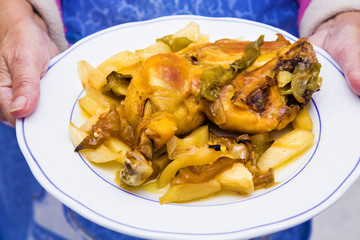 woman holding dish with pieces of roasted chicken