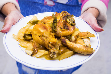 woman holding dish with pieces of roasted chicken