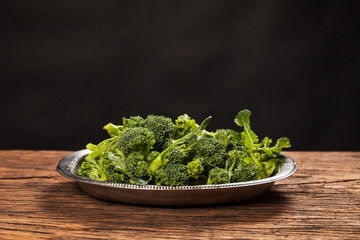 Fresh raw  broccoli bowl on a wooden table. Black background. Mediterranean food