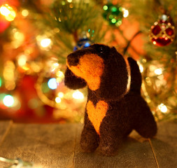 Symbol of new years 2018 dachshund dog. Bolt. New years greetings background. Fancy handmade toy from wool on bokeh Christmas background. Copyspace for congratulations.