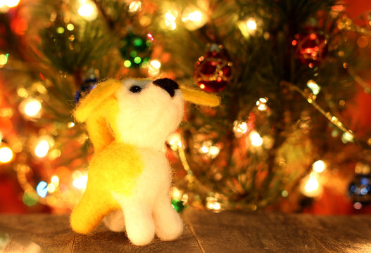 Symbol of new years 2018 yellow dog. Bolt. New years greetings background. Fancy handmade toy from wool on bokeh Christmas background. Copyspace for congratulations.