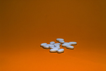 Tablets with calcium on a orange background. White pills on a colored background.