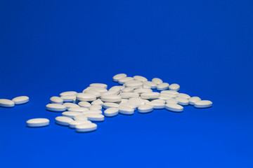 Tablets with calcium on a blue background. White pills on a colored background.