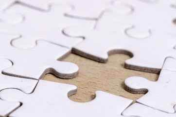 the last piece, white jigsaw/puzzle with one gap, over wooden table background, symbol of problem...
