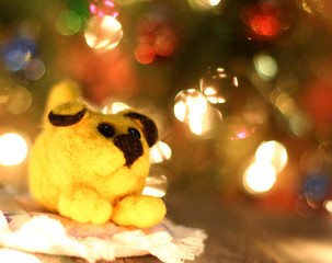 Symbol of new years 2018 yellow dog. Bolt. New years greetings background. Fancy handmade toy from wool on bokeh Christmas background. Copyspace for congratulations.