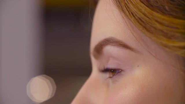 The makeup artist correcting the shape of eyebrow