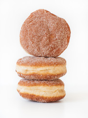 German fried donut, so called Krapfen, Berliner or Pfannkuchen, filled with rose hip jam and dusted with cinnamon sugar, traditionally eaten at carnival and at New Year's Eve on white background