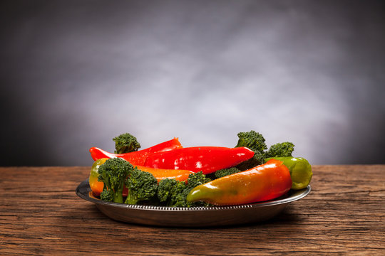 Fresh red pepperoni frigitelli and broccoli on a wooden table. Dark background. Vegan food