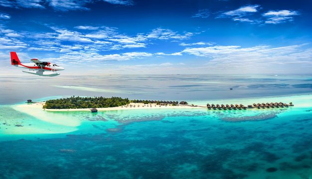 Wasserflugzeug fliegt &uuml;ber Malediven Insel mit t&uuml;rkisem Wasser und feinem Sandstrand