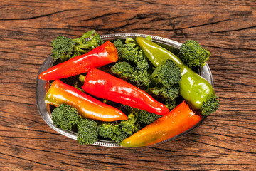 High view of fresh red pepperoni frigitelli and broccoli on a wooden table. Vegan food