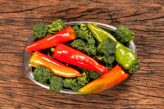 High view of fresh red pepperoni frigitelli and broccoli on a wooden table. Vegan food