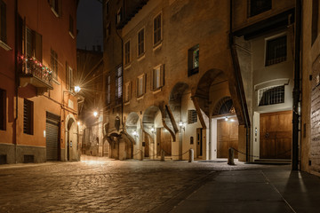 Fototapeta premium ancient old street of bologna in italy at night with lantern lights and stone paving