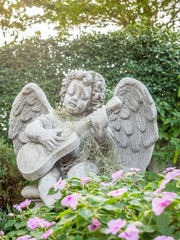 Playing guitar little angel statue in outdoor garden under evening light