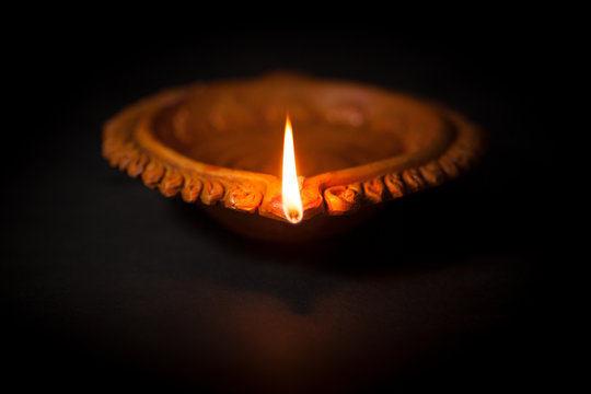 A beautiful Handmade Designer Clay Lamp with burning wick against the dark background. 